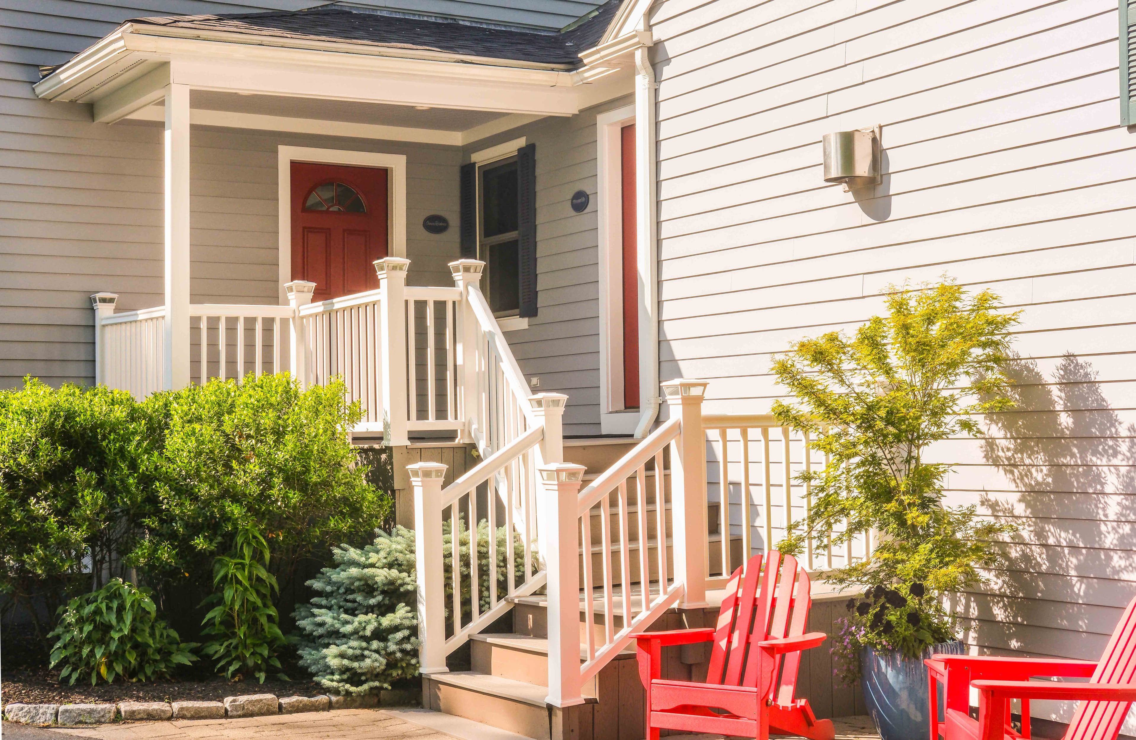 Private entrance off parking lot with outdoor seating and manicured gardens.