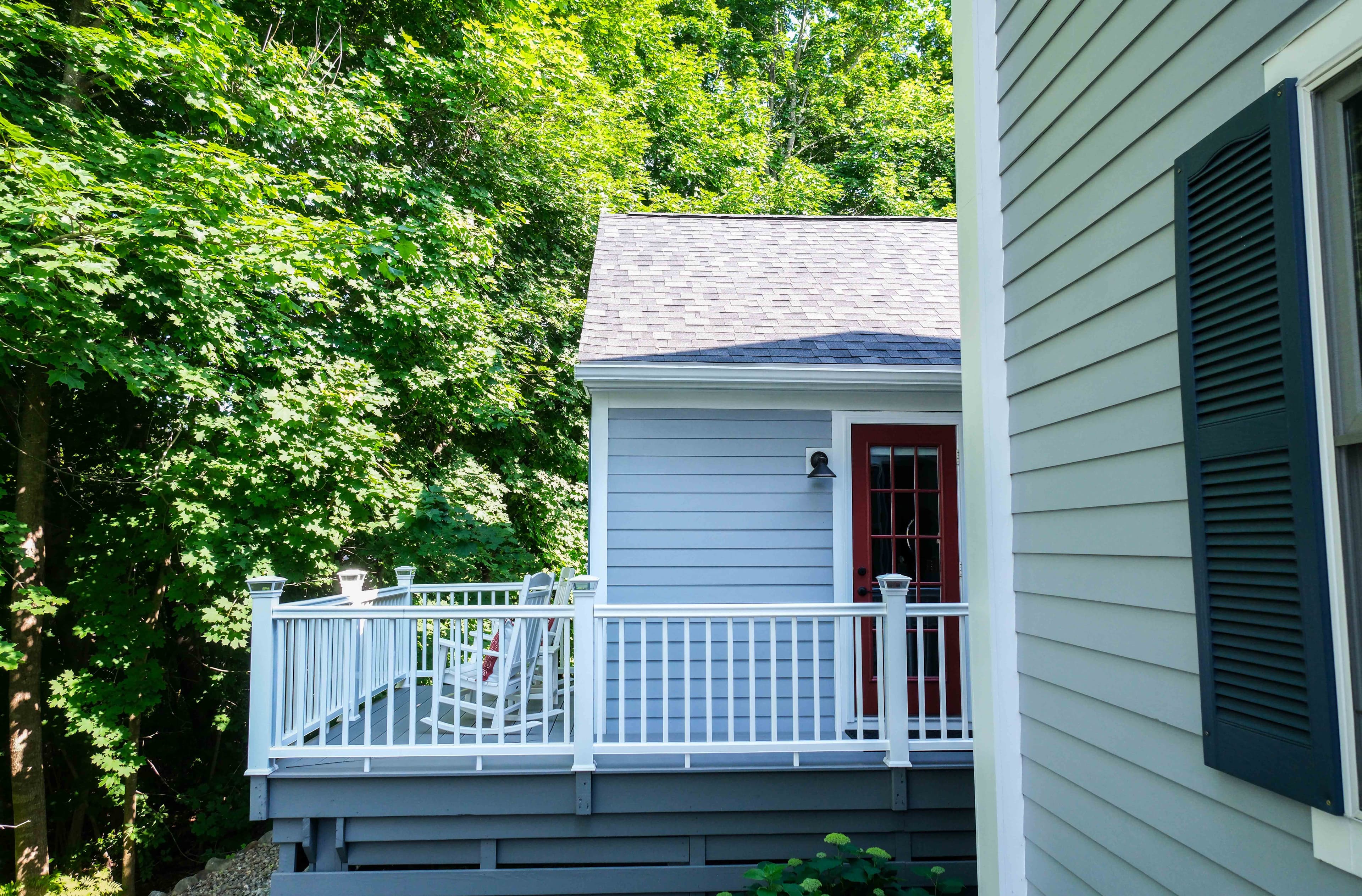 Private outdoor balcony with two rocking chairs and table.