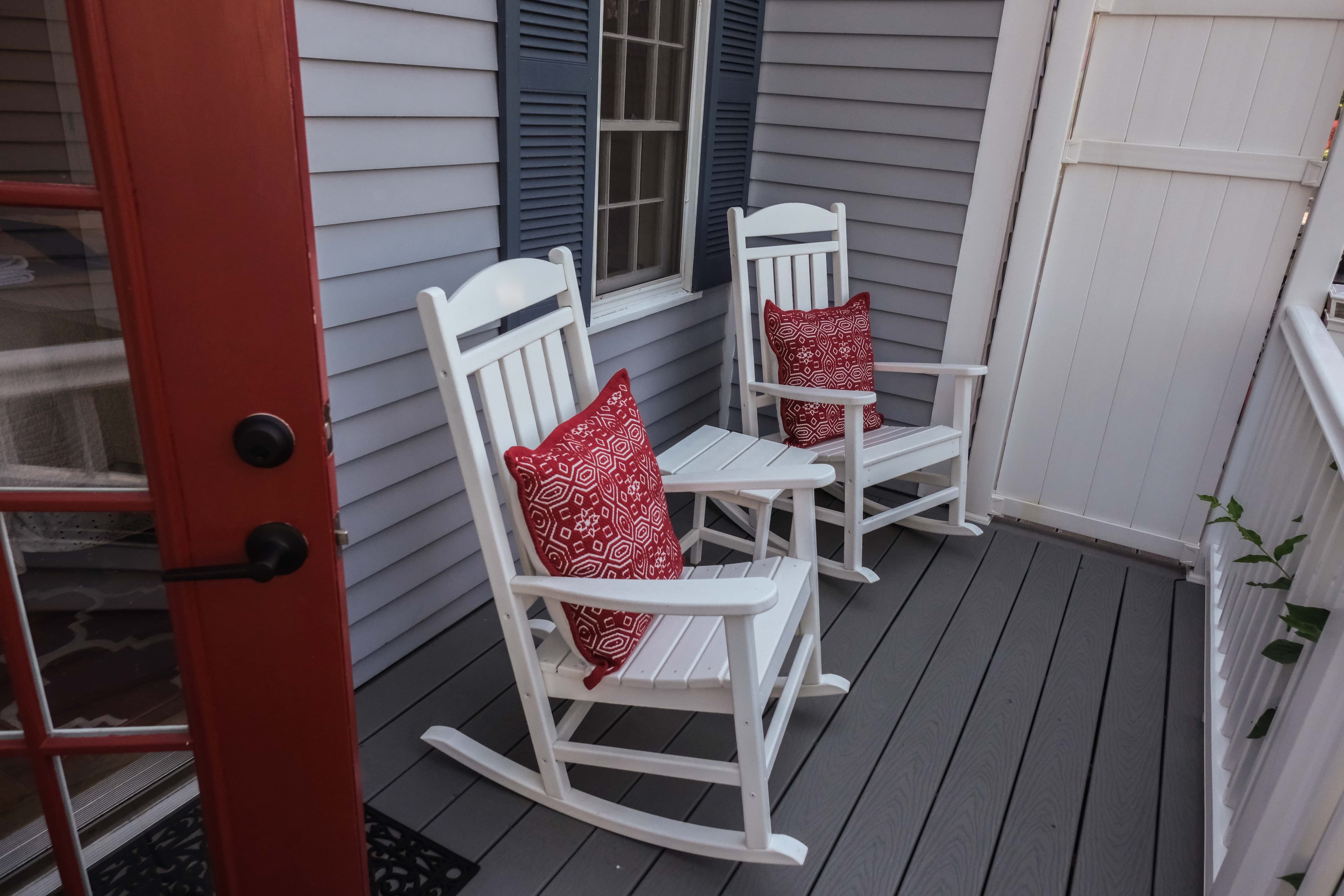 Private outdoor balcony with two rocking chairs and table.