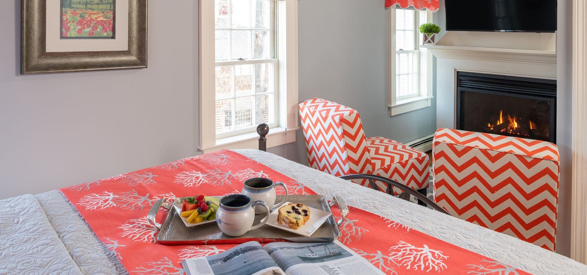 Cozy bedroom with orange accents, a tray of breakfast, and a fireplace.