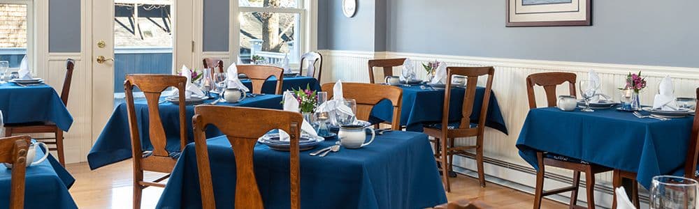 A cozy restaurant interior with wooden furniture and blue tablecloths set for dining.