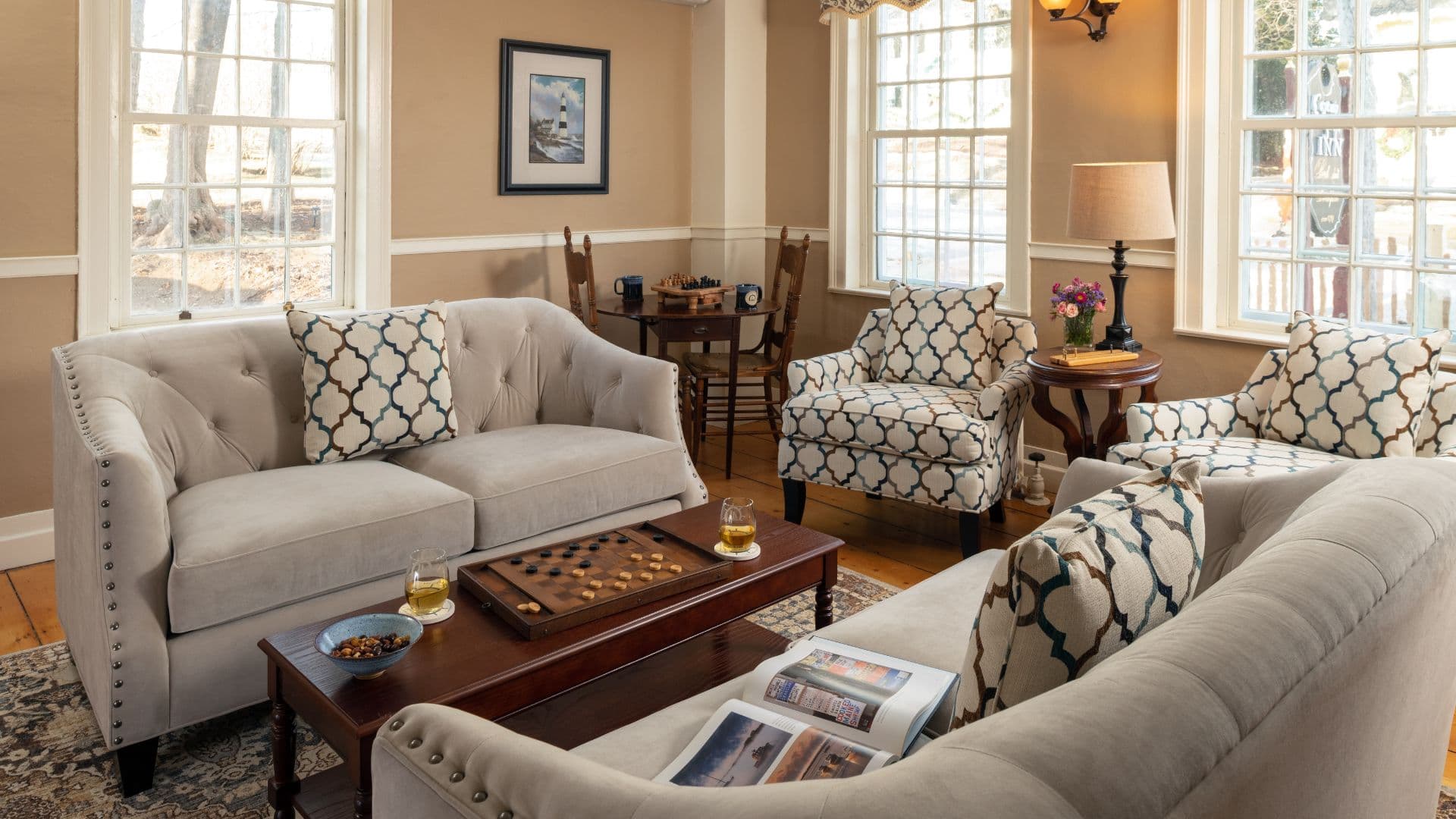 Cozy living room with a light sofa, patterned chairs, a coffee table, and large windows.