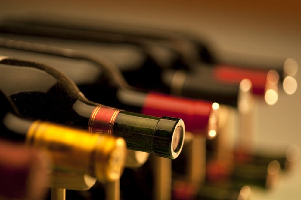 A close-up of several wine bottles lined up, showcasing various colored caps.