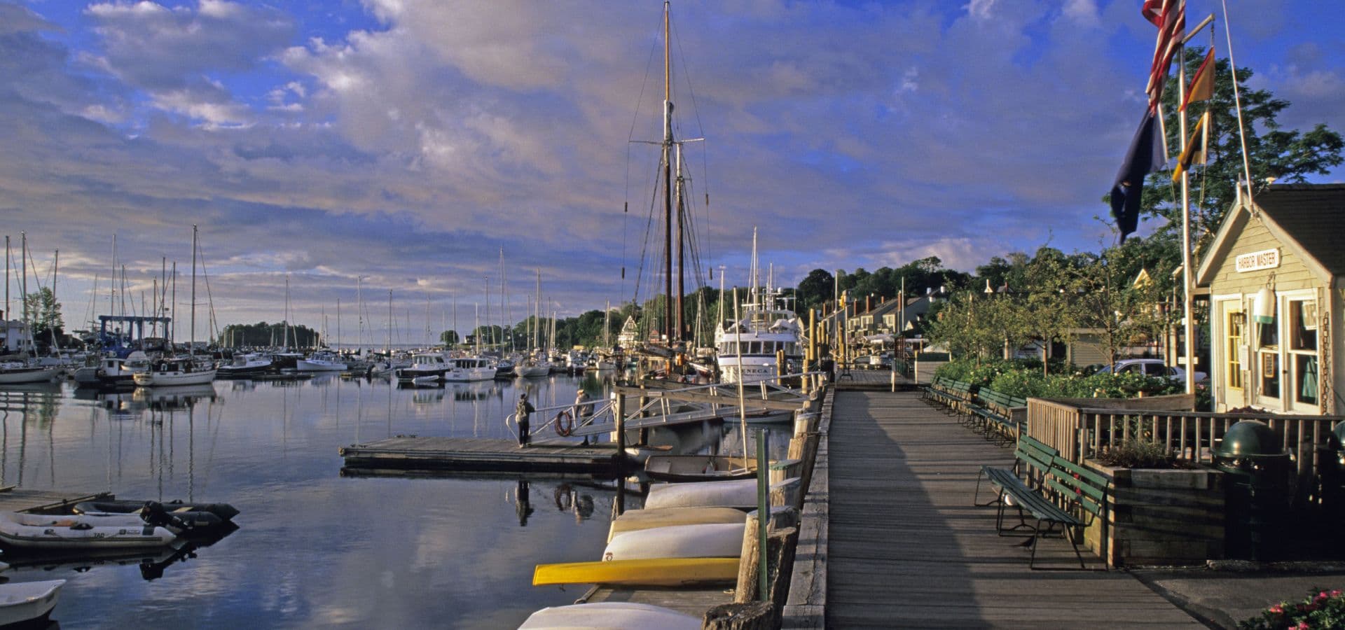 A peaceful marina scene with boats, a wooden dock, and a cloudy sky.