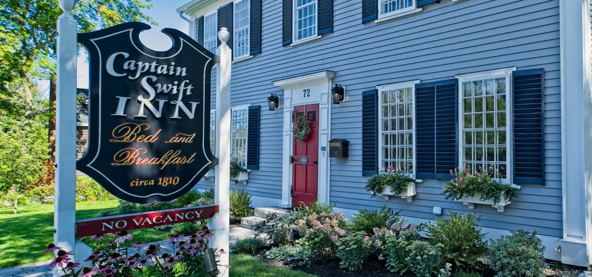 A historic blue house featuring a sign for Captain Swift Inn Bed and Breakfast.