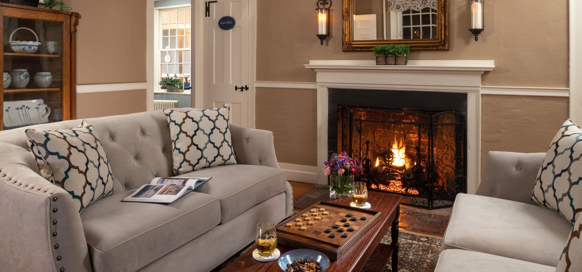 Cozy living room featuring a fireplace, elegant seating, and a coffee table with drinks and snacks.