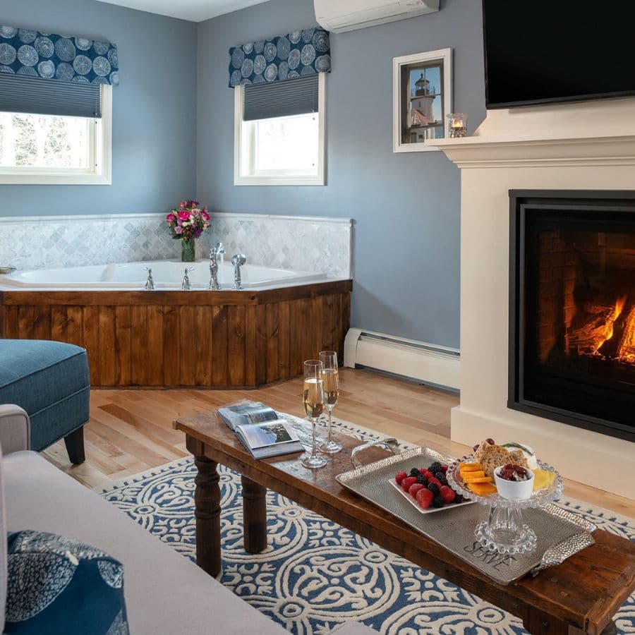 A cozy living area featuring a fireplace, a whirlpool tub, and a table set with snacks and drinks.