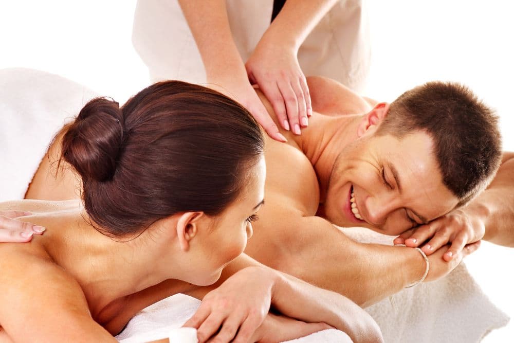A woman and a man are enjoying massages, smiling and relaxed.