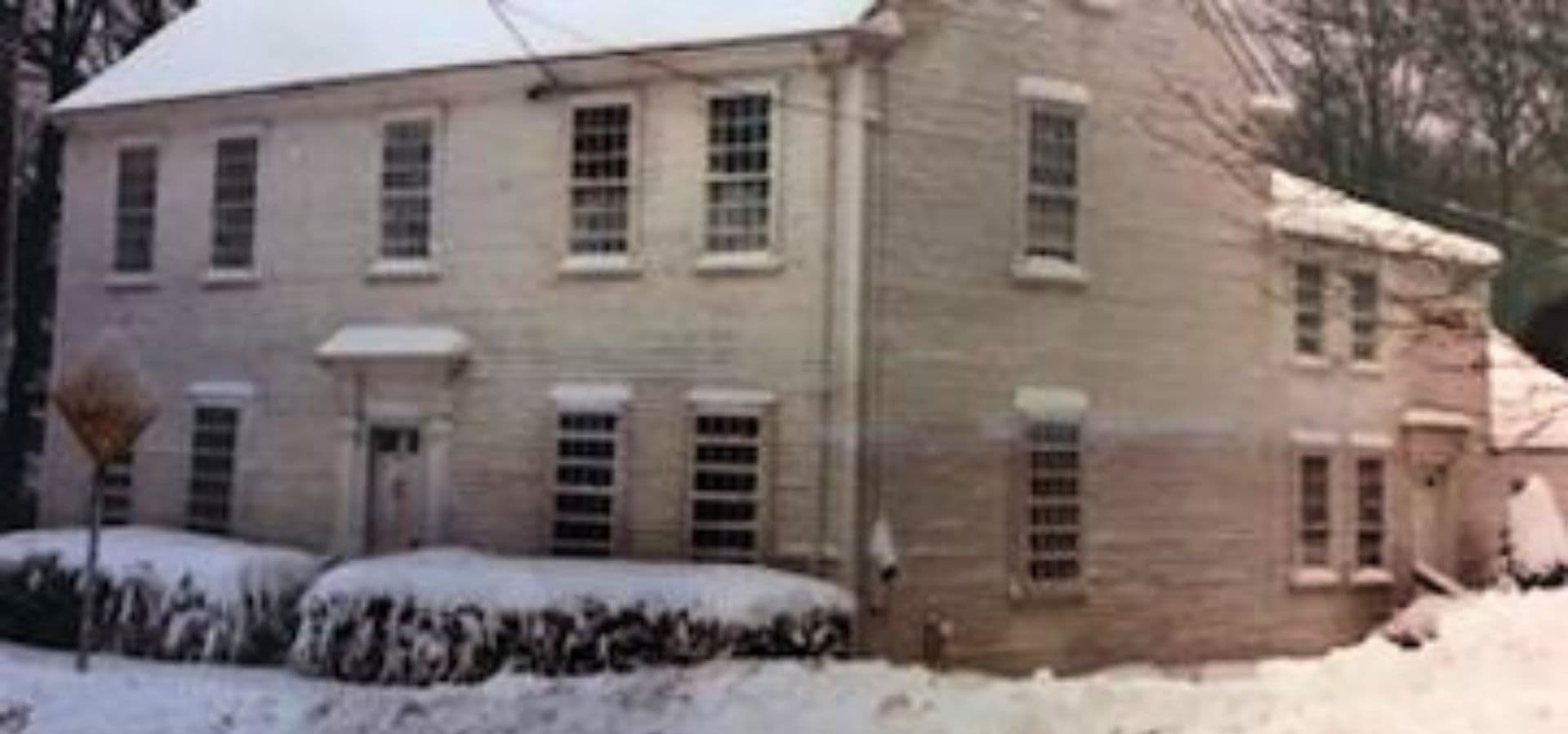 A two-story white house surrounded by snow.