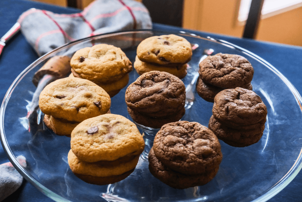 A glass plate holds an assortment of chocolate chip and chocolate cookies.