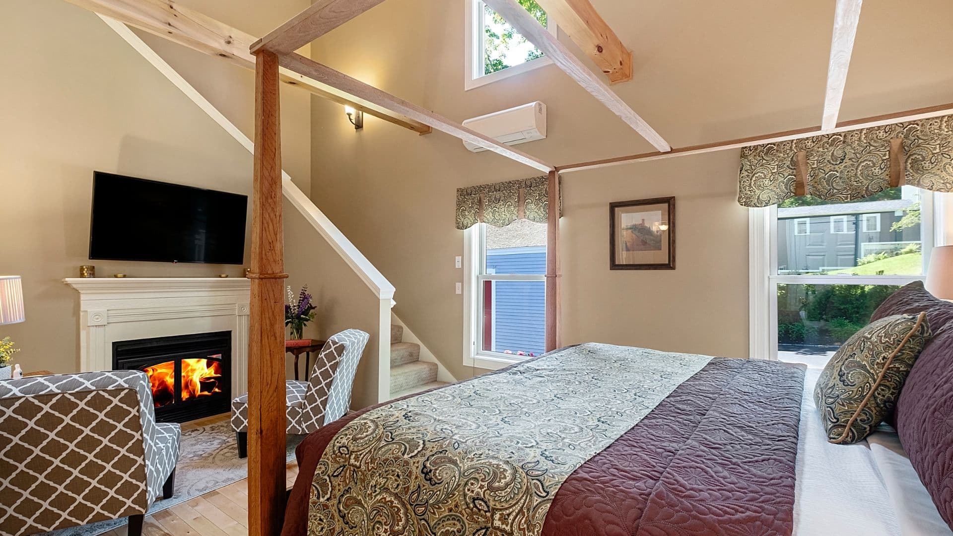 Cozy bedroom with a fireplace, large windows, and stylish furnishings.