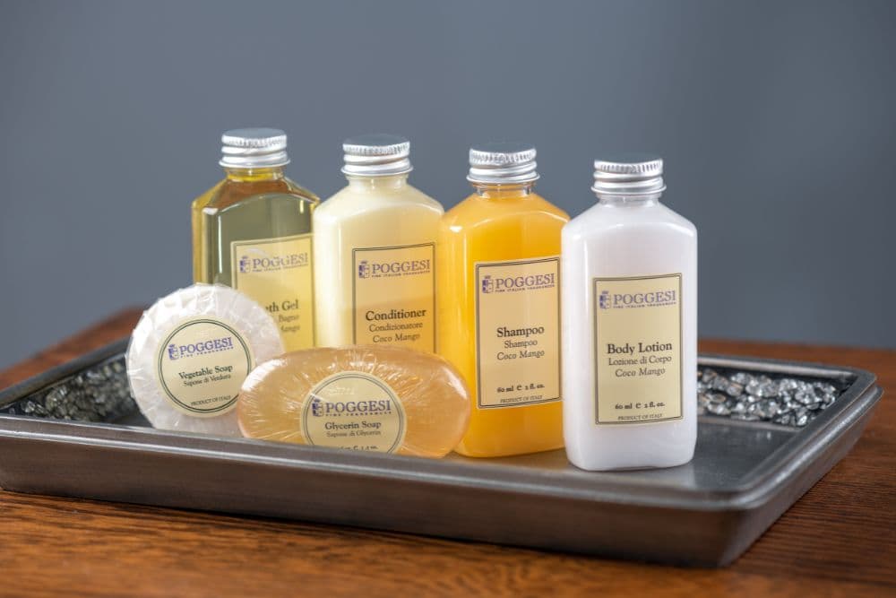 A tray displaying a collection of hotel toiletries including shampoo, conditioner, body lotion, and soap.